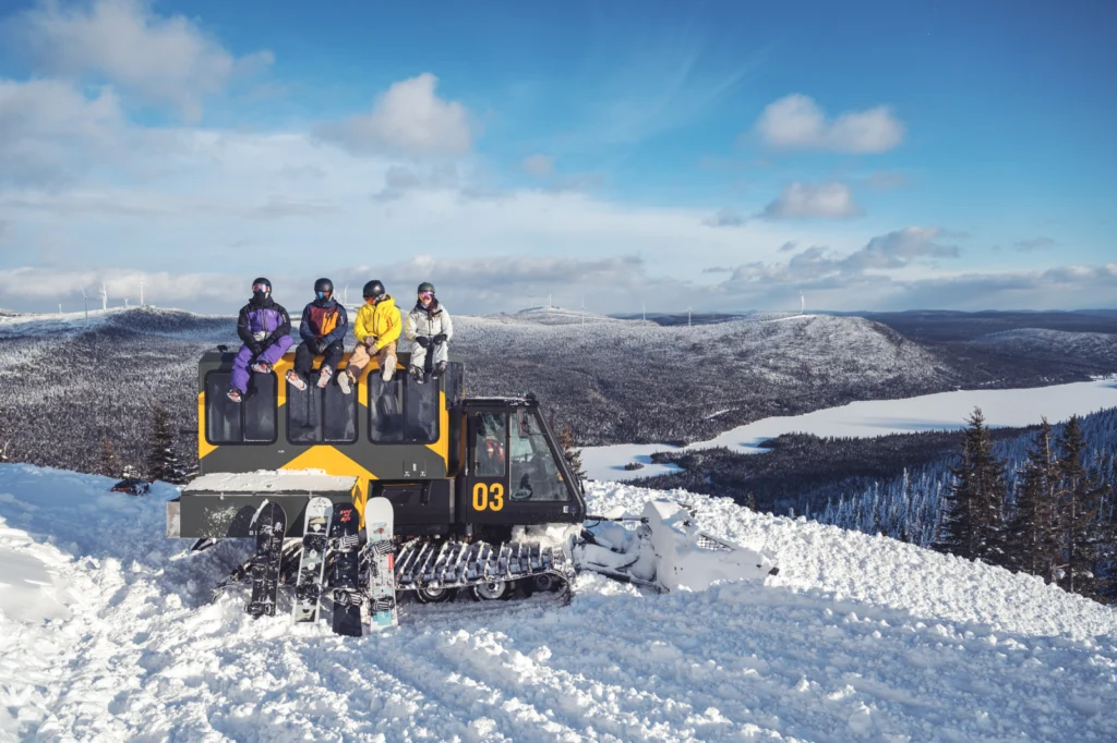 des skieurs posent sur le toit d'un catski chic-chac dans un paysage de montagnes de Gaspesie