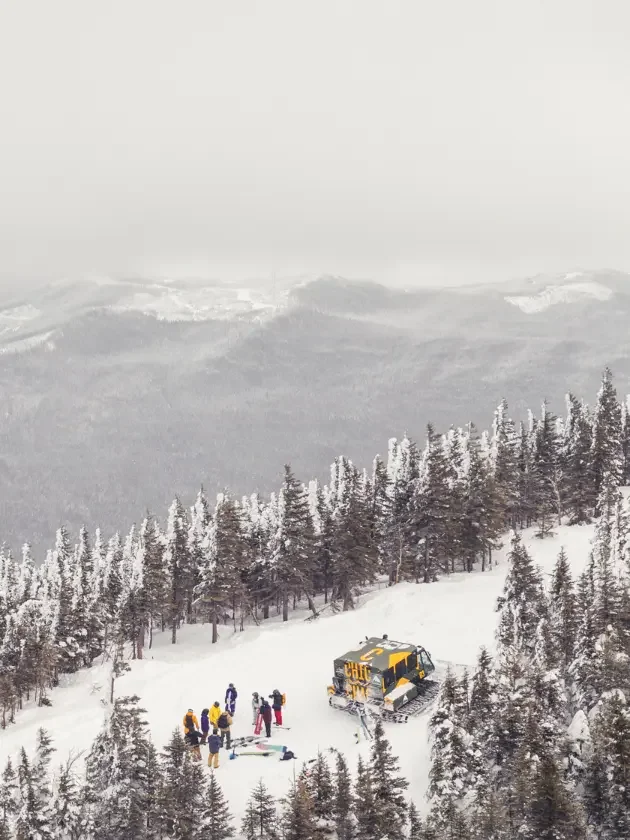 catski et groupe de skieurs dans un paysage enneigé de Gaspésie vu du ciel en plongée.