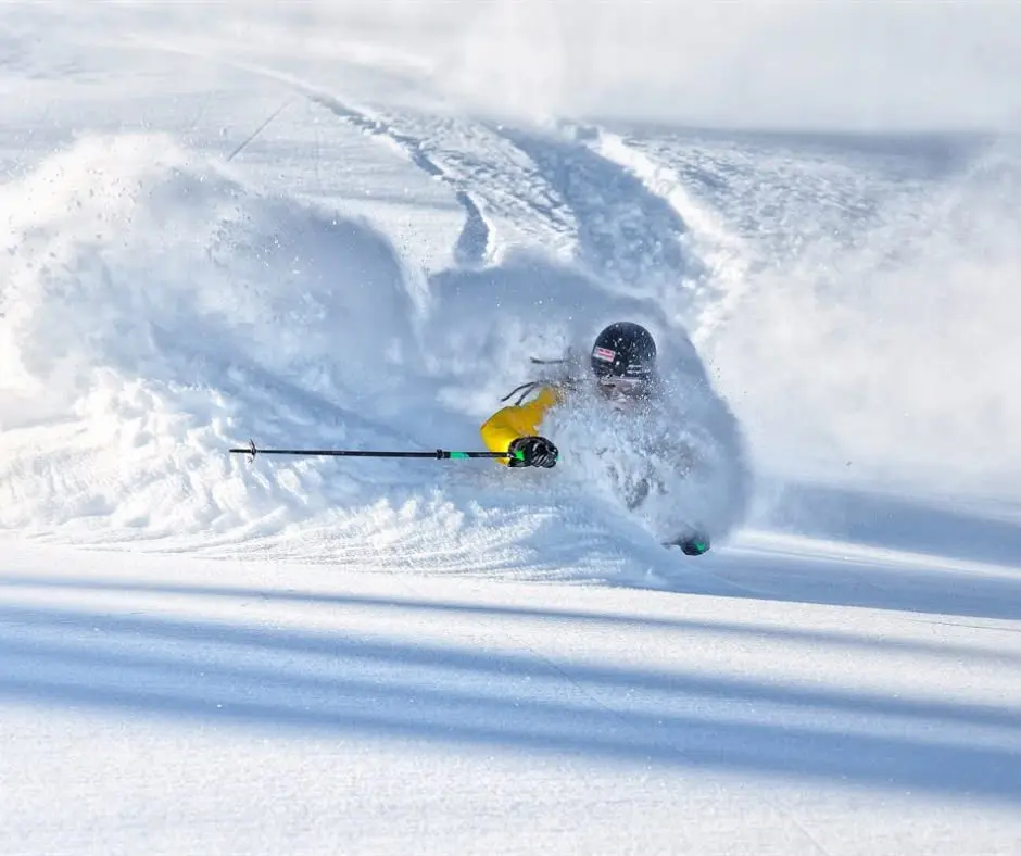 un freerider descend une piste dans un nuage de poudreuse