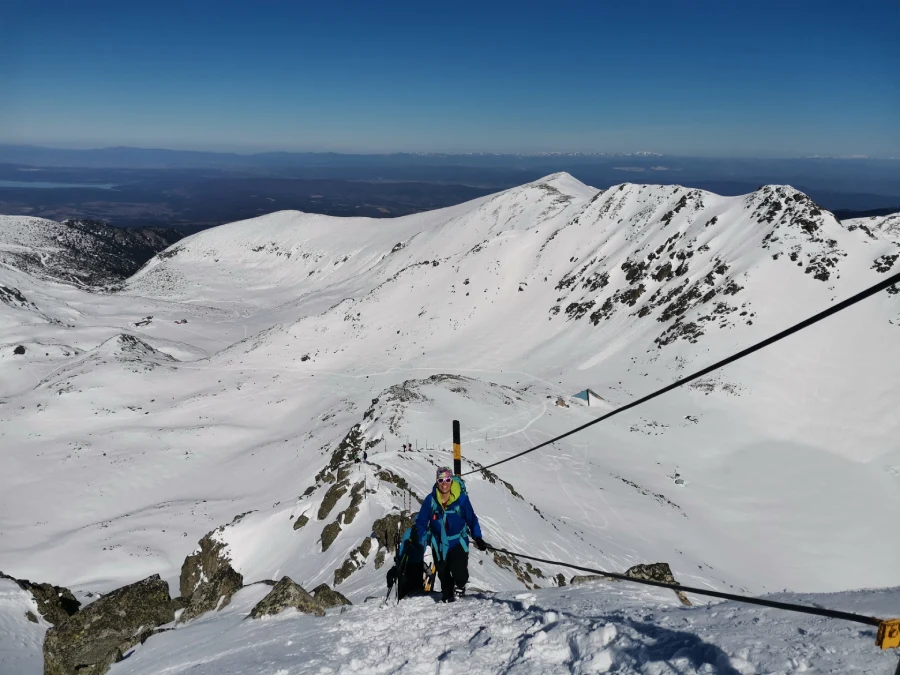 randonneurs ski en cordée vu de face gravissent un sommet sur une arête. Les sommets bulgares derrière à l'horizon